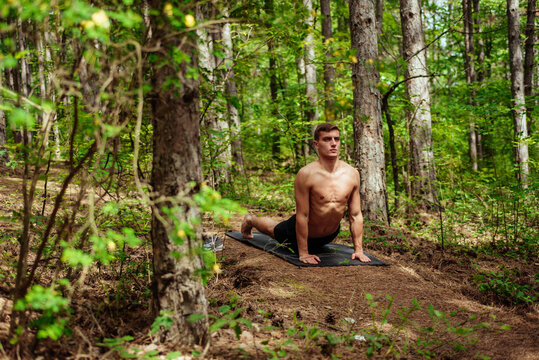 Flexible young man stretching body outdoors
