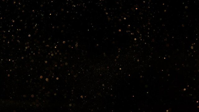 Super slow motion of glittering golden particles on black background. Shallow depth of focus. Filmed on high speed cinema camera, 1000 fps.