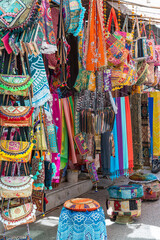 Fototapeta na wymiar Selling clothes, fabrics and gifts at local street market in holy city Pushkar, Rajasthan, India