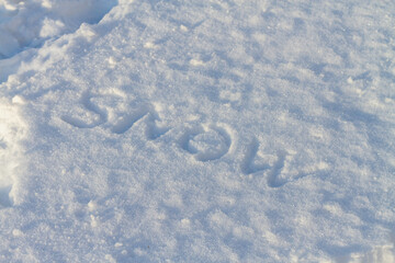 The word snow is written on white snow in winter on a frosty day
