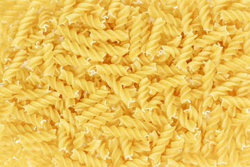 Yellow uncooked fusilli pasta texture as a food background.