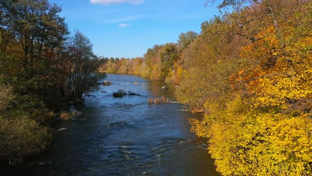 Fantastic picture of the flowing river among the forest. Colorful trees on a sunny autumn day. Aerial nature view.