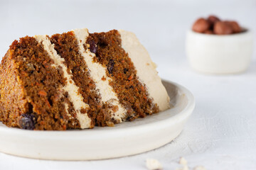 A piece of homemade carrot cake with coconut cream and nuts on a plate. Sugar, gluten, lactose free, vegan, healthy food.