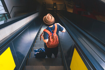 High angle and rear view of female traveler going down the escalator at subway station