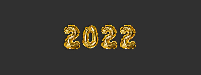 2022 golden foil balloons decor and Christmas snow with copy space on dark background. New Year concept