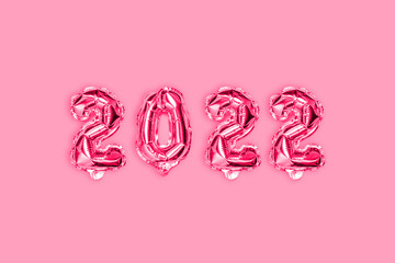 New Year's golden pink balloons decor on pink background. New Year and Xmas concept