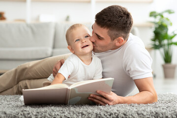 Fototapeta premium Child Care. Loving Father Reading Book And Kissing His Cute Toddler Son