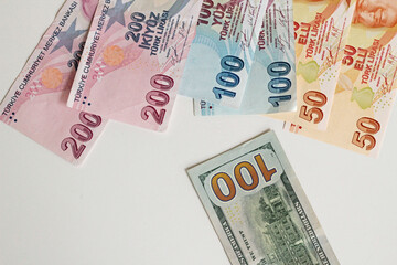 One hundred American dollars with Turkish money on white background