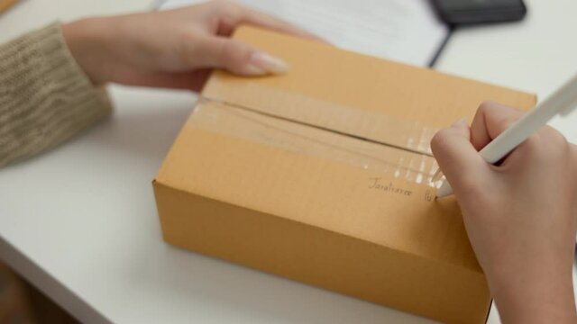 Close up shot Business woman hand writing name and address to sending product to customer. Online business working at home. Startup Small business owner entrepreneur.
