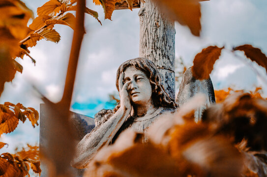 Old stone statue in the autumn park. Weeping angel.