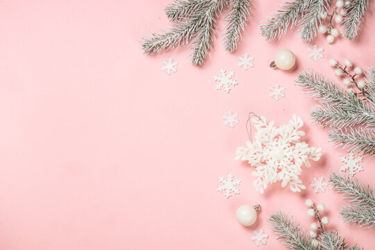 Christmas decorations at pink background. Fir tree and white christmas decorations. Flat lay image with copy space.