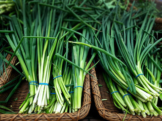 Chives On A Brown Basket In A Market. Background Texture Of Chives, Green Onions, On The Counter