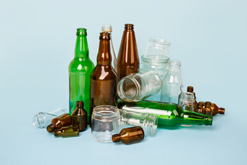 Separate collection of glass garbage. Colorful bottles and cans for recycle. Eco friendly concept. Recyclable glass waste on blue: empty glass jars and bottles. Zero waste. Save the planet. Go green