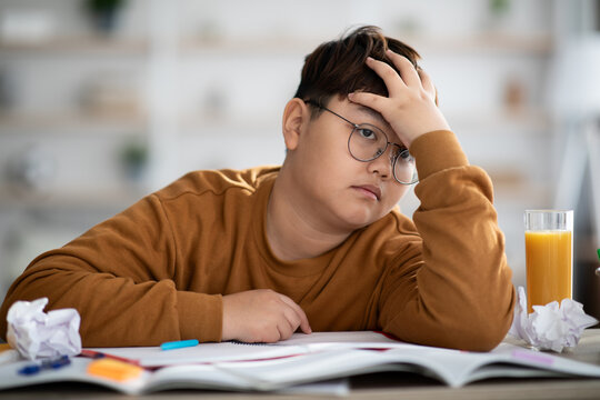 Asian schooler dreaming about something while doing homework