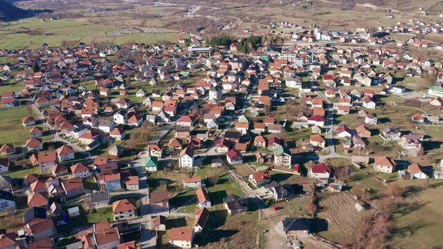 Gusinje Montenegro - aerial drone panorama of a small town in Europe on a sunny day. Houses with red roofs on a large green field. Townscape of suburban settlement (village).