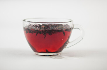 Karkade. Tea drink in a glass. Red liquid in a glass. Dried petals. Hibiscus. Sudanese rose