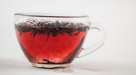 Karkade. Tea drink in a glass. Red liquid in a glass. Dried petals. Hibiscus. Sudanese rose
