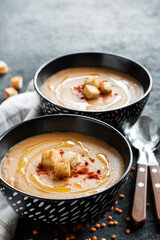 Lentil cream soup with paprika and crouton in black ceramic bowls