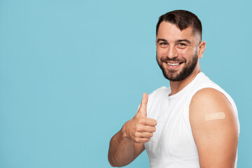 Happy mature caucasian male with beard showing thumb up and shoulder with band aid after injection - obrazy, fototapety, plakaty