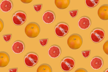 Creative pattern with fresh whole and sliced grapefruit on yellow background. Minimal fruit concept.