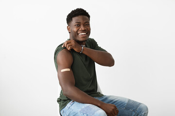 Cheerful handsome black man showing adhesive band on shoudler