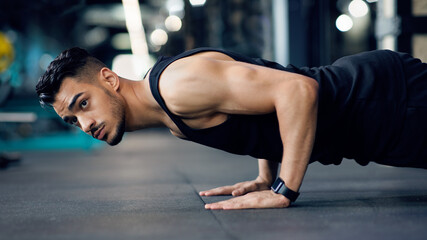 Fototapeta na wymiar Sporty Young Arab Man Making Floor Push Up Exercise In Gym