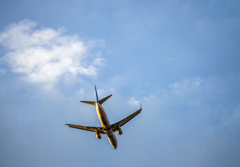 Flying plane against the blue cloudy sky before landing with the landing gear released