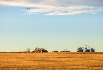 A rural farm homestead on a harvested field on the Coloradan Prairies with the airplanes in the sky