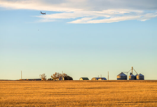 A rural farm homestead on a harvested field on the Coloradan Prairies with the airplanes in the sky