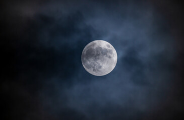 Full moon against the black cloudy night sky