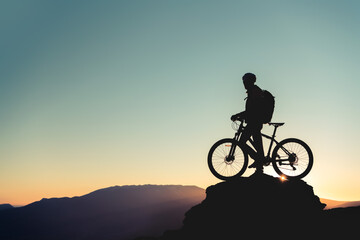 Fototapeta na wymiar Cyclist's silhouette on big rock against sunset