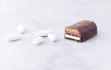 Energy bar and sports supplements on bright stone background. Soft focus. Close up. Copy space.	