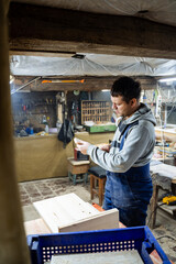 Crafting. Joiner and his woodworking tools. Work in the workshop. Creation of household items from wood. Special clothes and gas mask