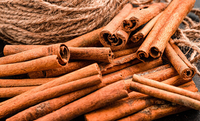 cinnamon dry in the form of sticks, with a rope, on a black background
