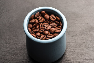 coffee beans from a blue mug, on a black backgroundcoffee beans from a blue mug, on a black background