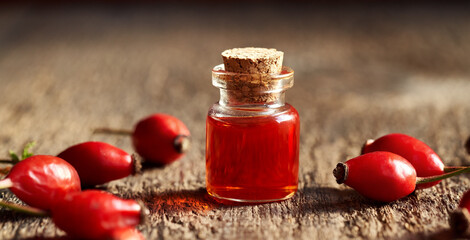 A bottle of rosehip seed oil with fresh rose hips