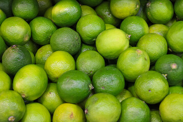 Abstract snapshot of a large number of green juicy limes for sale in a store in a box