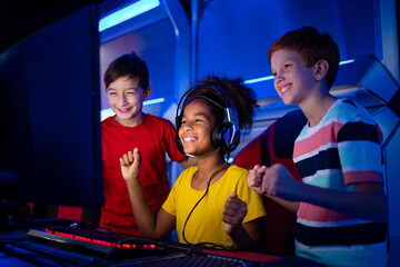 Cheerful kids at game room playing favorite video game and supporting female gamer.