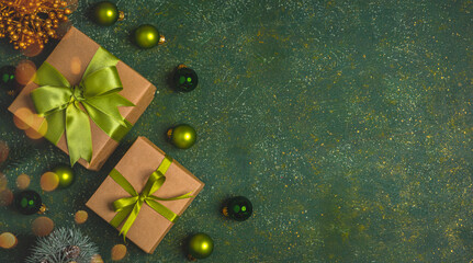 Christmas gift box with green ribbon and green christmas balls on the green background