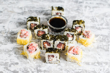 Sushi rolls with cheese, caviar, fish and sauce on a light concrete background with copy space