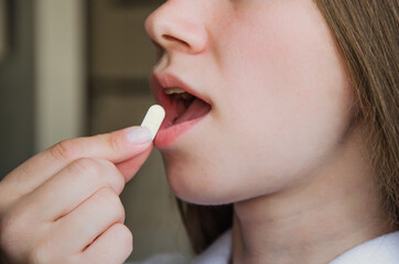 girl puts a white pill in her mouth. medicine concept. pill