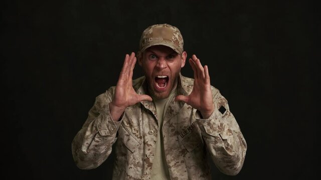 Angry military man screaming at the camera in black studio
