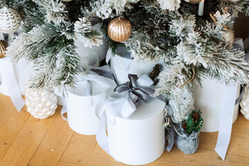 Christmas gifts under a snowy tree, beautiful white boxes. Gift for the new year. Beautiful box with a bow.