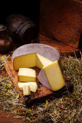 Traditional aged mountain cheese of the Alps offered as loaf and piece at a rustic wooden chalet