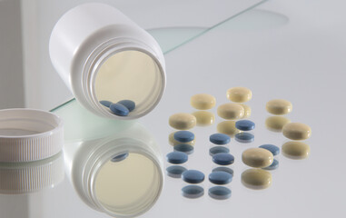 blue and yellow coated tablets in front of opened white plastic bottle