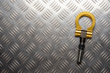Sport style car tow hook on the metal background with copy space.