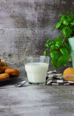 Vertical shooting, milk glass, next to it muffins and doughnuts on a plate, decorative contour, base and bottom of stone. Copy space.