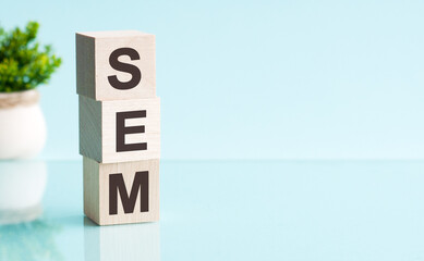 SEM word in wooden blocks on table. blue background, copy space