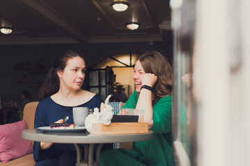 two women talking and drinking coffee in cafe
