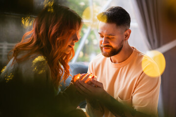 A loving couple holds a magical light in their hand. Warm light illuminates the face of the man and woman.